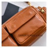 A close-up of a tan leather crossbody bag with a front flap pocket, gold-tone hardware