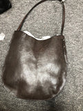 A dark brown leather shoulder bag with a slouchy crescent shape and a long strap