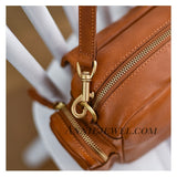 A close-up of a brown leather bag with gold-tone hardware