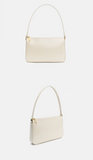 An off-white leather shoulder bag with a curved top handle and gold-tone hardware