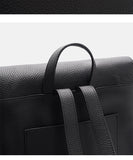 Close-up of a black pebbled leather bag showing a top handle and dual shoulder straps