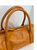 A close-up of a tan leather handbag with double top handles