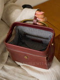 A close-up of a person holding a structured reddish-brown leather handbag