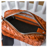 A close-up of a woven leather cosmetic pouch in warm cognac brown