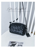 A black woven leather crossbody bag with a long strap