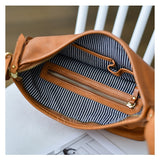 A tan leather handbag shown open