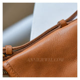 Close-up of a tan leather shoulder bag showing the texture of the leather, a strap detail
